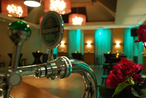 Heineken-tap met op de achtergrond de zaal in turquoise licht