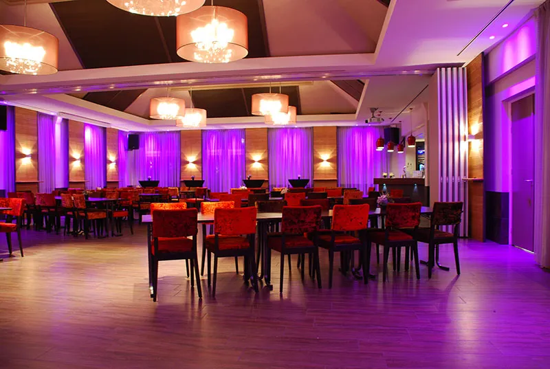 Feestelijk gedekte zaal met paarse verlichting